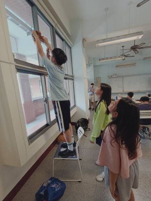 Mika helps Chelsea and Celia put up decorations in the Grade 7 classroom